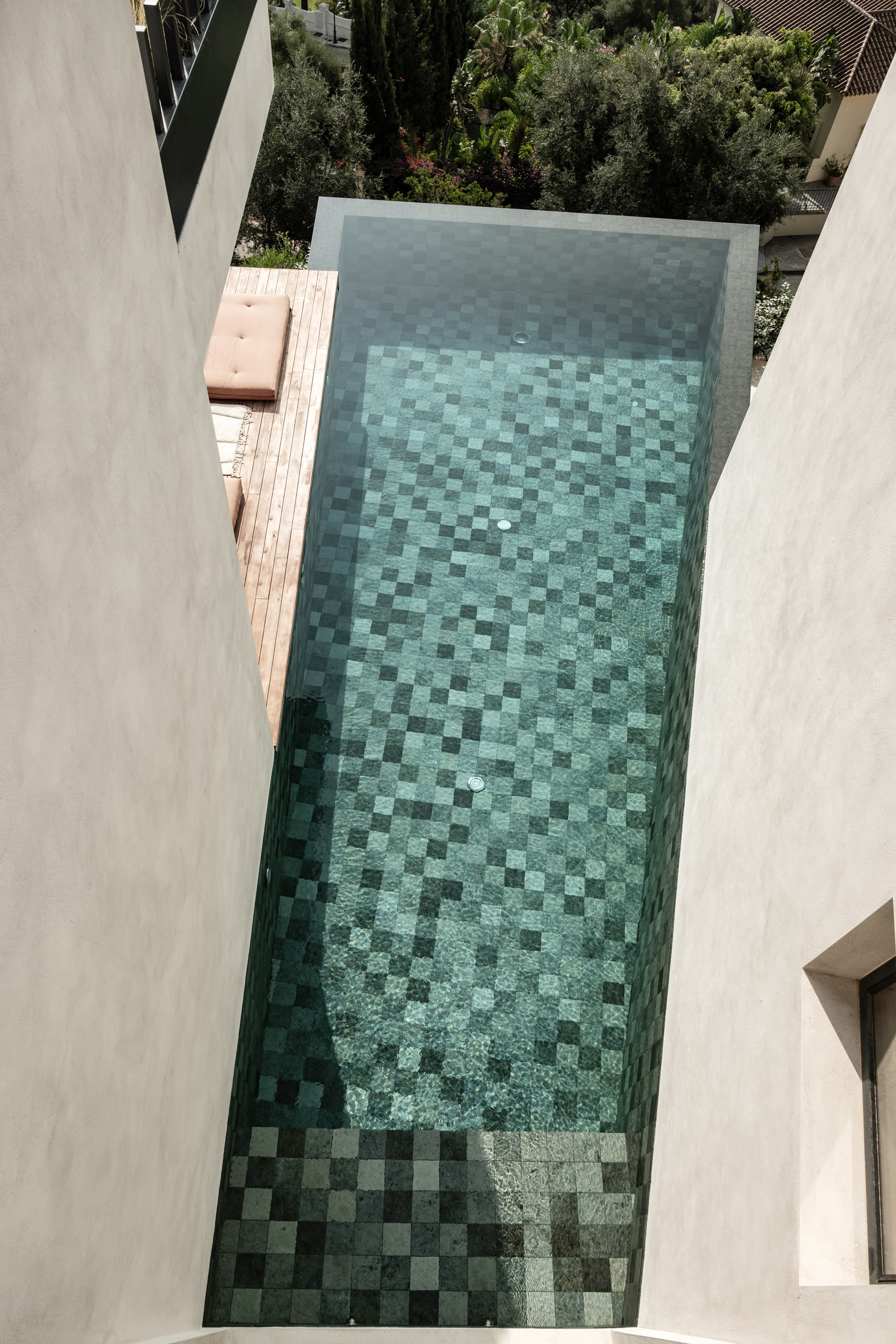 The plunge pool seen from directly above, green mosaic and timber deck